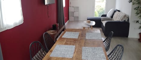 Un comedor con una mesa de madera, cuatro sillas y un televisor en la pared.