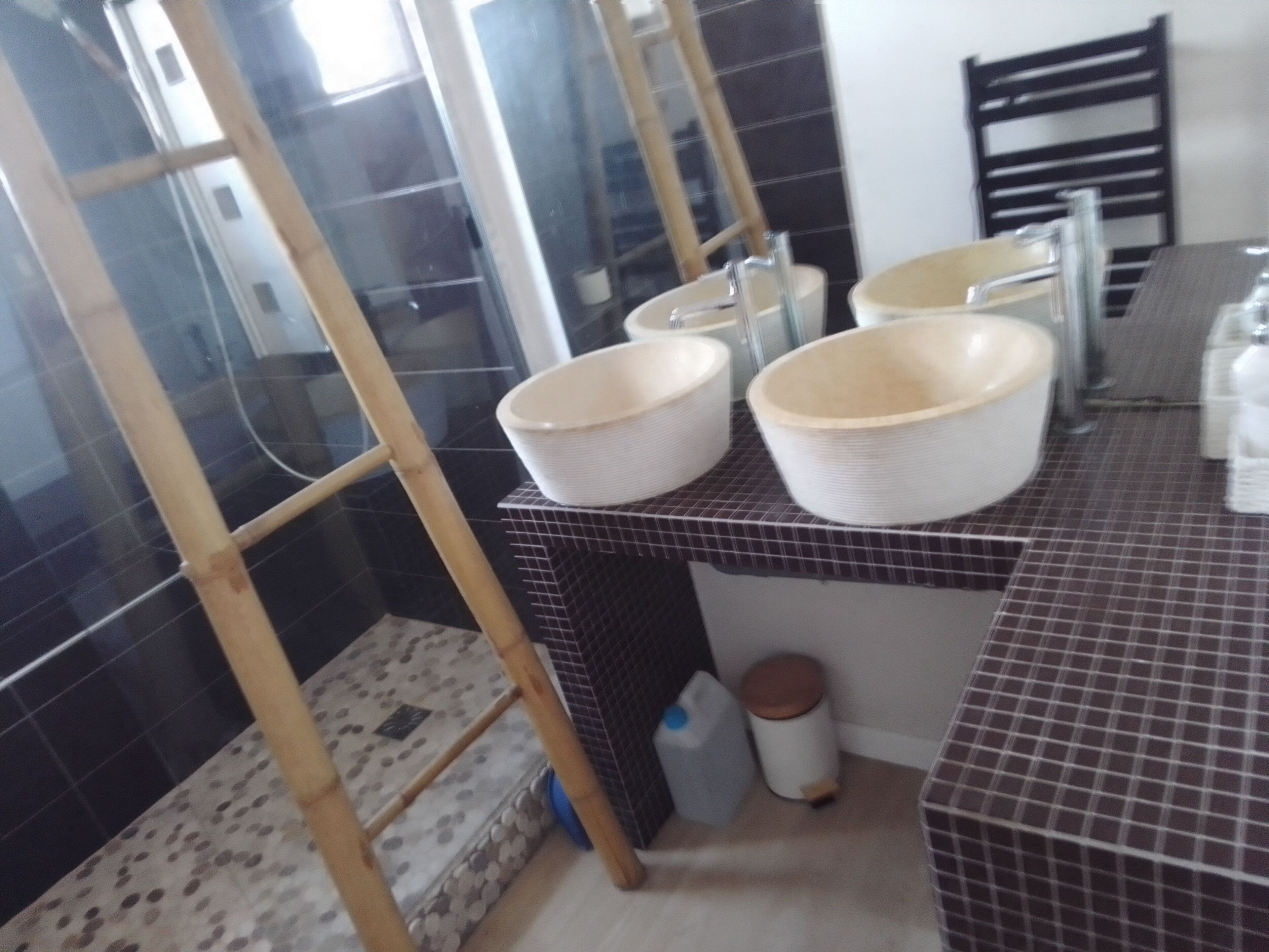 Une salle de bain avec un sol carrelé, un espace douche et un lavabo avec un miroir.