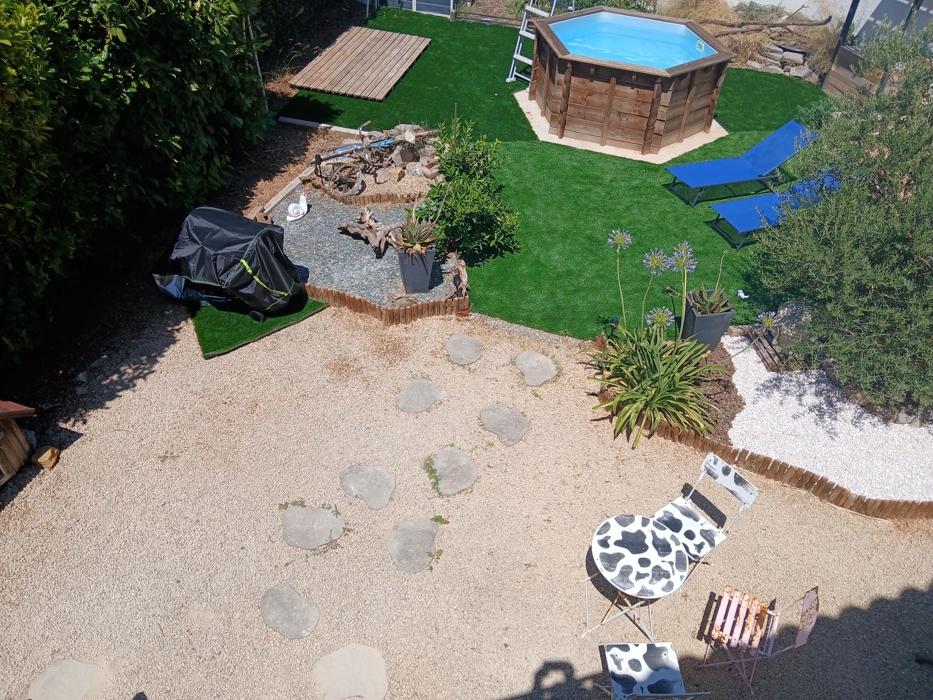 A backyard with a wooden hot tub, a small deck, and a lawn.