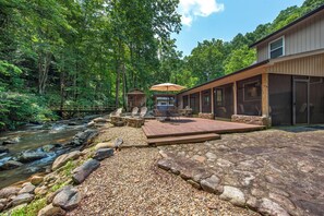 A riverside property with a wooden deck, outdoor seating, and a view of the forest. - Escape to Creek Haven, a stunning riverside retreat nestled on Norton Creek Road (Gatlinburg)