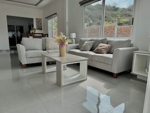 A modern living room with a grey sofa, a white coffee table, and a vase with flowers. - Azul Paradise in San Clemente, Ecuador (San Clemente)