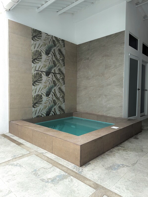 A rectangular hot tub with a tiled border, surrounded by walls with a leaf pattern and a plain tiled wall. - Azul Paradise in San Clemente, Ecuador (San Clemente)