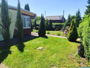 A well-maintained garden with a lawn, a wooden fence, and a variety of trees. - Idyllic Bungalow Surrounded by Greenery (Arendsee (Altmark))