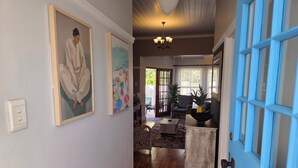 A hallway with a blue door, a painting, and a chandelier.