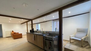 A modern kitchen with a central island, wooden cabinets, and a built-in oven. - Newly built holiday cottage in a mill by the Loir River (Marboué)