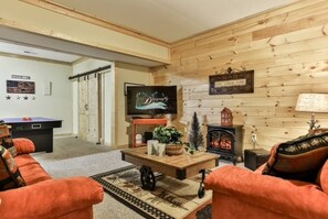 Ein Wohnzimmer mit Fernseher, Kamin und Billardtisch.