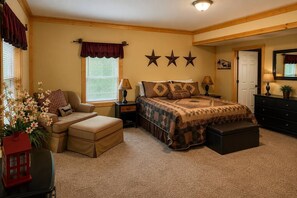 A bedroom with a bed, nightstands, a chair, a dresser, and a window with curtains. - River Resort Retreat | Hot Tub & Game Room | Pets (Ellijay)