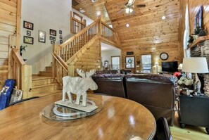 A wooden interior with a staircase, a round table with a moose sculpture, and leather sofas. - River Resort Retreat | Hot Tub & Game Room | Pets (Ellijay)