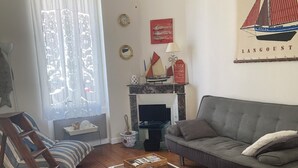 A living room with a sofa, armchair, coffee table, and a fireplace. - Fisherman's cottage on the Fouras Peninsula (Charente-Maritime) (Fouras)