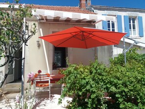 A patio with a red umbrella, a table, and chairs. - Fisherman's cottage on the Fouras Peninsula (Charente-Maritime) (Fouras)