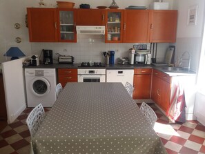 A compact kitchen with a washing machine, a microwave, and a dining area with a polka dot tablecloth. - Fisherman's cottage on the Fouras Peninsula (Charente-Maritime) (Fouras)