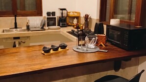Une cuisine avec un plan de travail en bois, un évier, un four à micro-ondes et deux tabourets de bar noirs.