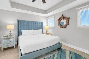 Ein Schlafzimmer mit einem Bett, Nachttischen, einem Deckenventilator und einem Spiegel.