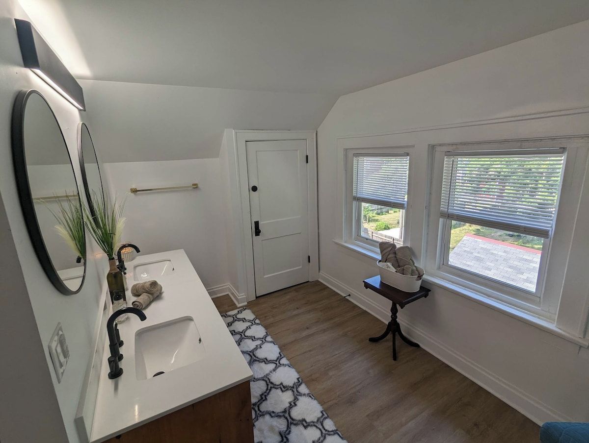 A bathroom with a white sink, a mirror, a towel rack, and a window with blinds.