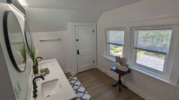 A bathroom with a white sink, a mirror, a towel rack, and a window with blinds.