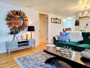 A living room with a green sofa, a coffee table, a wall-mounted globe, and a decorative wall piece. - Vintage garden level apt in fabulous,  quiet tree lined SugarHouse neighborhood (Salt Lake City)