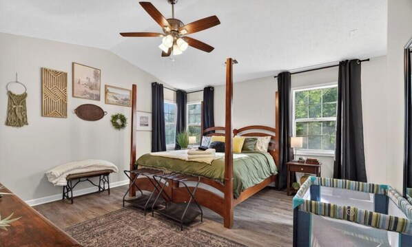 A four-poster bed with a wooden headboard, a ceiling fan, and a view of a tree through the window. - Colemans Landing - Inviting 3/2 Woodstock Ranch (Woodstock)