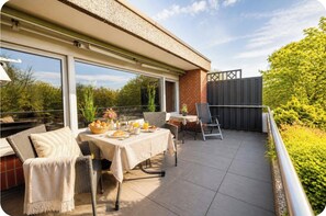 A covered patio with a table set for breakfast, outdoor seating, and a view of the surrounding greenery. - Sielblick Upper Floor with XXL Balcony, 74 m² (Bad Oeynhausen)