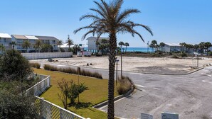 Una propiedad frente a la playa con una palmera, un estacionamiento y edificios al fondo.