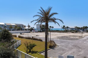 Ein Hotel direkt am Strand mit einer Palme, einem Parkplatz und Gebäuden im Hintergrund.