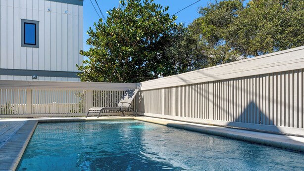 Una piscina con cubierta de madera y cerca blanca.