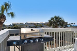 Ein Char-Broil Grill auf einem Balkon mit Blick auf ein Strandhotel und Palmen.