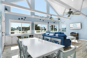 A bright room with a white table and chairs, a blue sofa, and a ceiling fan.