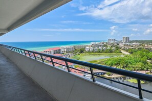 Uma varanda com vista para um horizonte costeiro, incluindo edifícios e uma extensão de água.