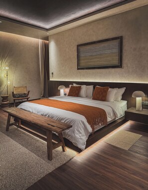 Ein modernes Schlafzimmer mit einem großen Bett, Nachttischen, einer Bank und einem Wandbild.
