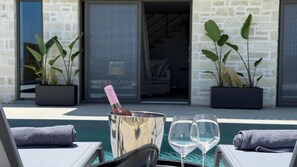 A poolside area with lounge chairs, a champagne bottle in a bucket, and two glasses. - Sunrise Village Aptera Private Pool Villa II (Chania)