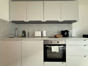 A modern kitchen with a built-in oven, a coffee maker, and a toaster. - Chic 1-Bed Flat in Sheffield City Centre (Sheffield)
