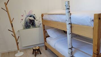 A bunk bed with a birch tree trunk decoration, a radiator, and a small stool with a bird design.