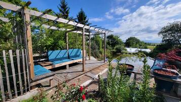 Una terraza de madera con un sofá azul y una estructura de pérgola.