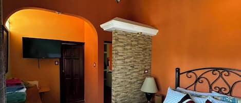 Un dormitorio con una cama, un escritorio, un televisor y un pilar de piedra.