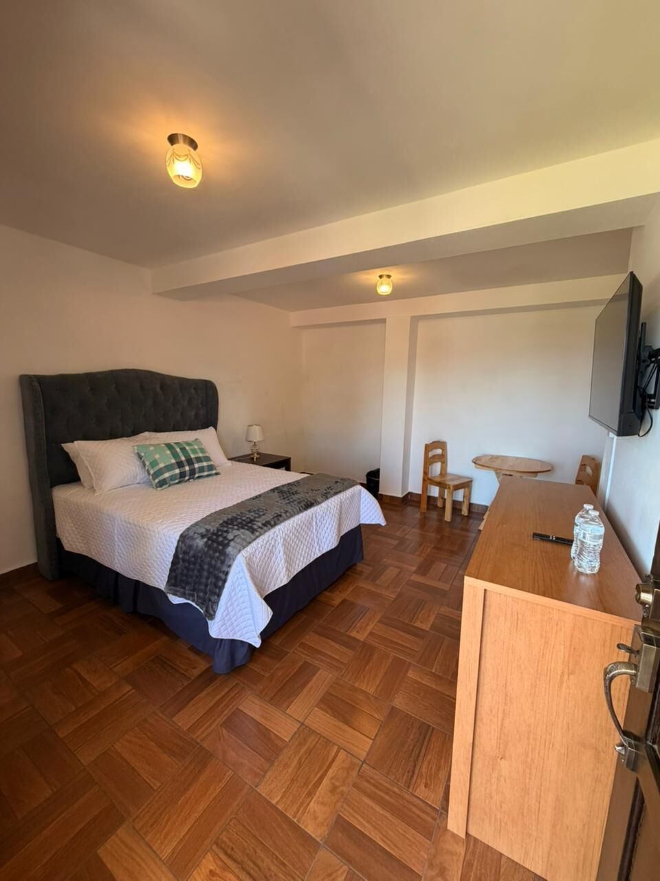 Une chambre d’hôtel comprenant un lit, une table de chevet, une chaise, un bureau en bois et un téléviseur.