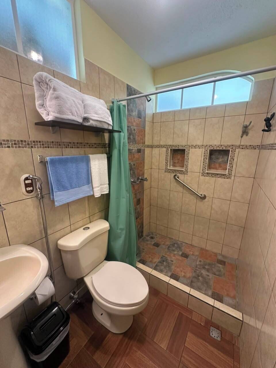 Un baño con inodoro, lavamanos, ducha y zona de ducha con azulejos.