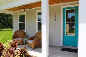 A house with a porch, two wicker chairs, a teal front door, and a number '652' on the wall. - Beautiful pet friendly three bedroom home with Pool near beach and attraction's (St. Augustine)