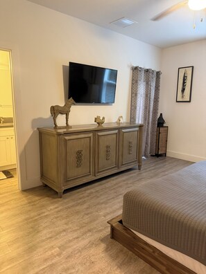 A bedroom with a bed, a wooden dresser, a flat-screen TV, and a framed picture on the wall. - Beautiful pet friendly three bedroom home with Pool near beach and attraction's (St. Augustine)