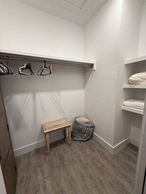 A walk-in closet with a wooden bench, a clothing rack, and shelves with folded towels. - Beautiful pet friendly three bedroom home with Pool near beach and attraction's (St. Augustine)
