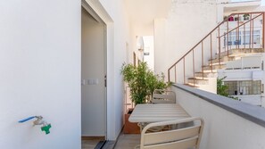 A narrow balcony with a table and chairs, a potted plant, and a staircase leading to an upper floor. - T2 Moderno c/Varanda em Portimão by Lovelystay (Portimão)