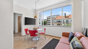 A modern living room with a flat-screen TV, red chairs, a round table, and a sofa with cushions. - T2 Moderno c/Varanda em Portimão by Lovelystay (Portimão)