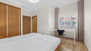 A hotel room with a bed, a desk, and a window with curtains. - T2 Moderno c/Varanda em Portimão by Lovelystay (Portimão)
