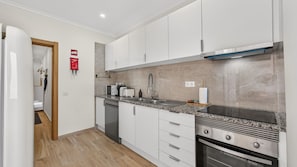 A modern kitchen with white cabinets, a stainless steel range hood, a built-in oven, and a granite countertop. - T2 Moderno c/Varanda em Portimão by Lovelystay (Portimão)