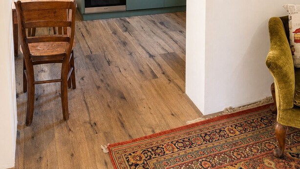 Cozinha compacta com área de refeições, piso de madeira e tapete estampado.