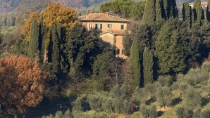 Uma casa rural rodeada por árvores e colinas.