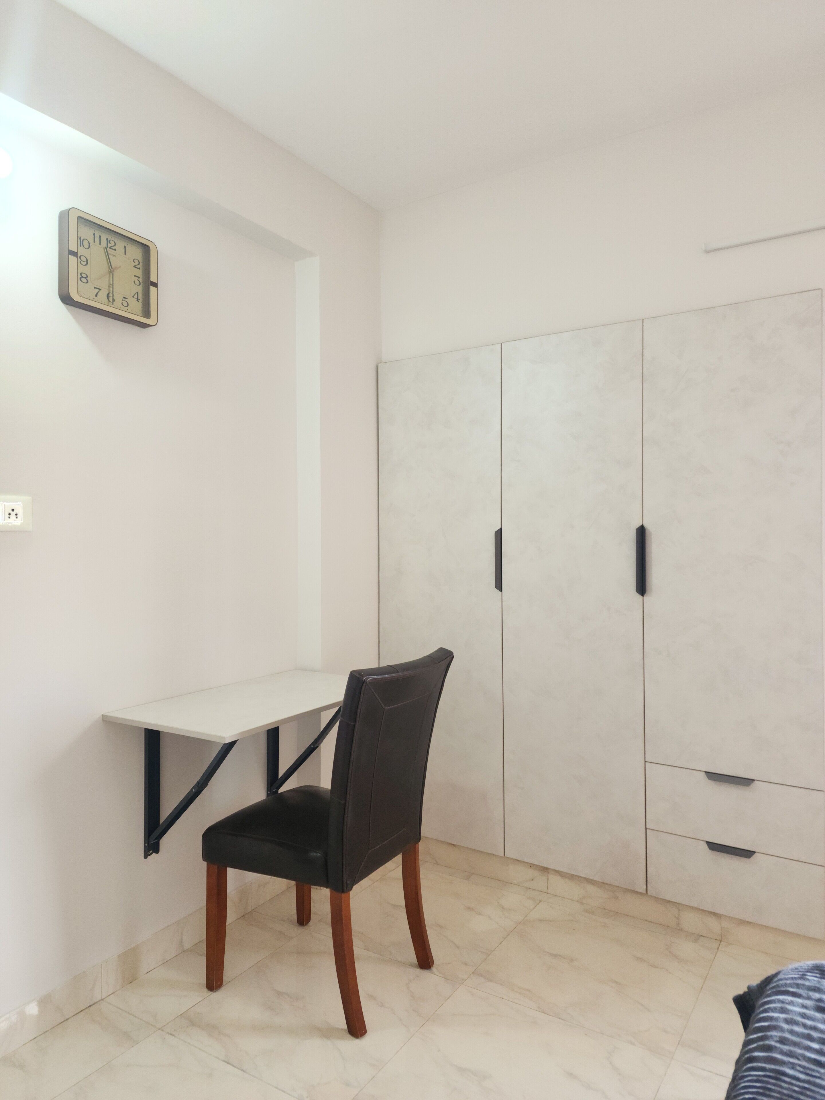 Une pièce comprenant un bureau, une chaise, une armoire et une horloge murale.