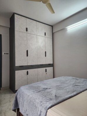 Ein Schlafzimmer mit einem Bett, einem Kleiderschrank, einem Deckenventilator und einer Lampe.