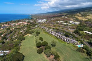 Ett flygbildsbild av en kustort med en golfbana, fastigheter vid stranden och ett stort hotellkomplex.