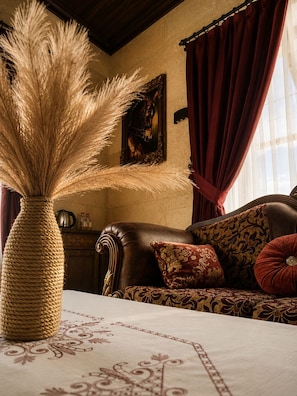 Una habitación con un jarrón grande de fibras naturales, un sofá estampado y un cuadro en la pared.