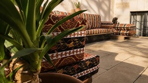 Een gestreept zithoekje in een binnentuin, met een potplant op de voorgrond.